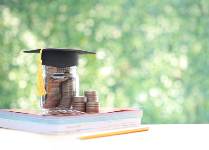 money and graduation hat on textbooks